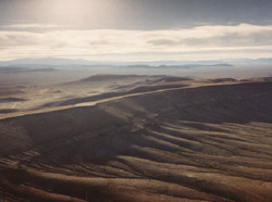 Aerial view of Yucca Mountain, looking northwest, showing the desert environment. The proposed geologic repository would be located about 300 meters (1,000 feet) below the eastern slope of the mountain.
